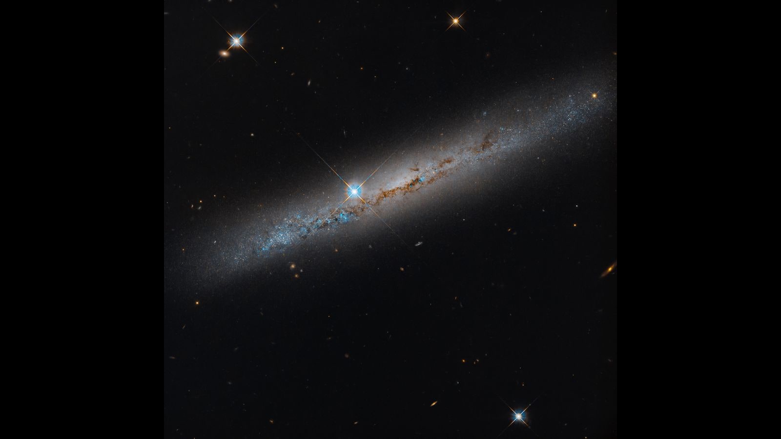 옆면(에지온)으로 보이는 나선은하 NGC 1827을 담은 허블 우주망원경 이미지. 은하 중심부 왼쪽에 회절 스파이크를 가진 밝은 전경 별이 있다. 정사각형 이미지로 양옆에 검은 띠가 있다.