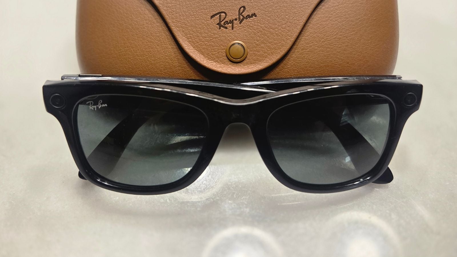 茶色の充電ケースの前に置かれた、黒色の第1世代Ray-Ban Metaスマートグラス。